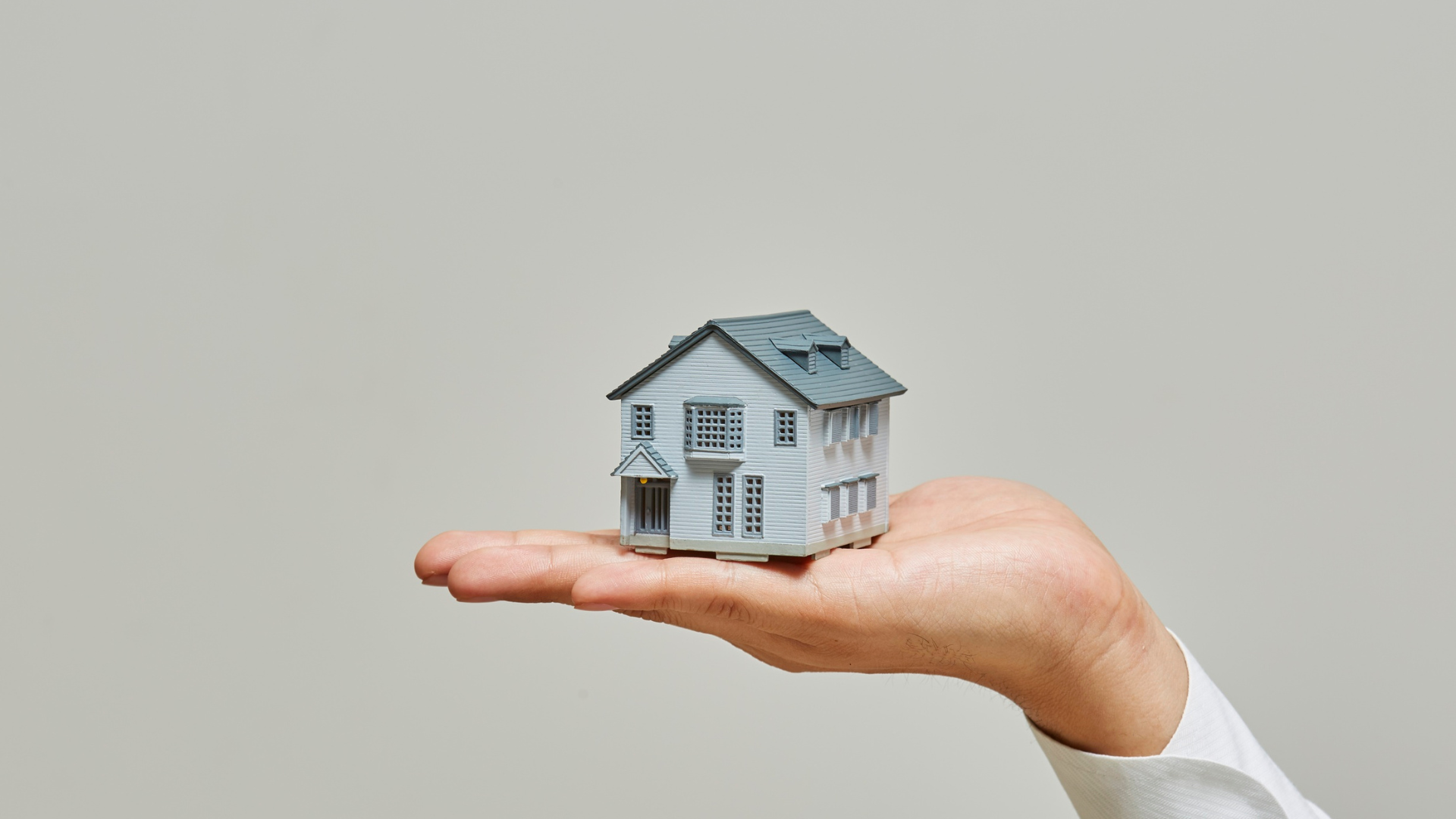 Mano sosteniendo una maqueta de casa